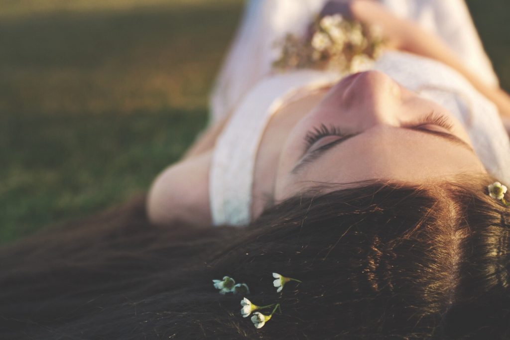 flowers in hair, woman lying down on grass